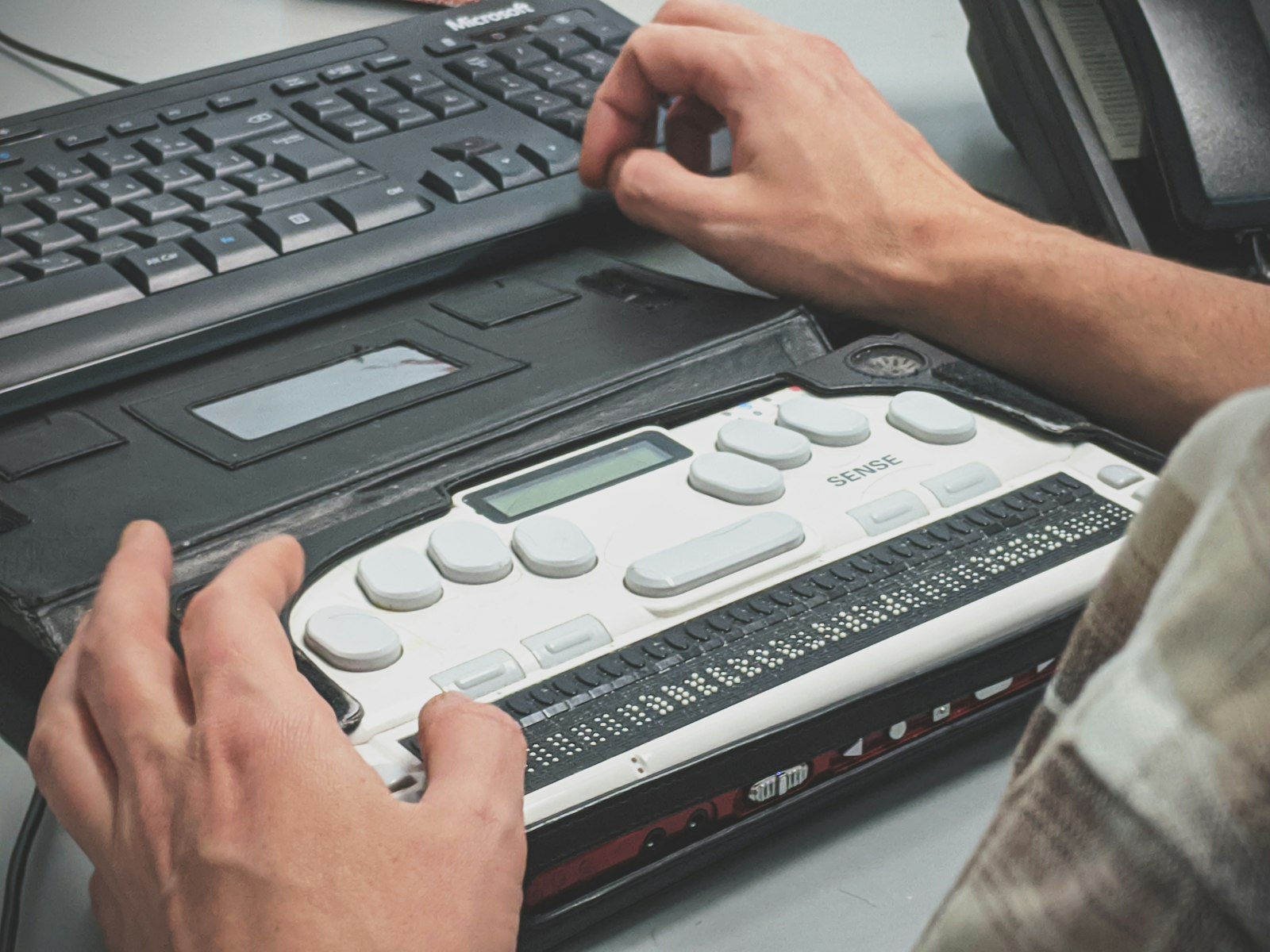 Barrierefreie Website: Was das BFSG für dein Unternehmen bedeutet 2 Hände bedienen eine Braillezeile neben einer Computertastatur