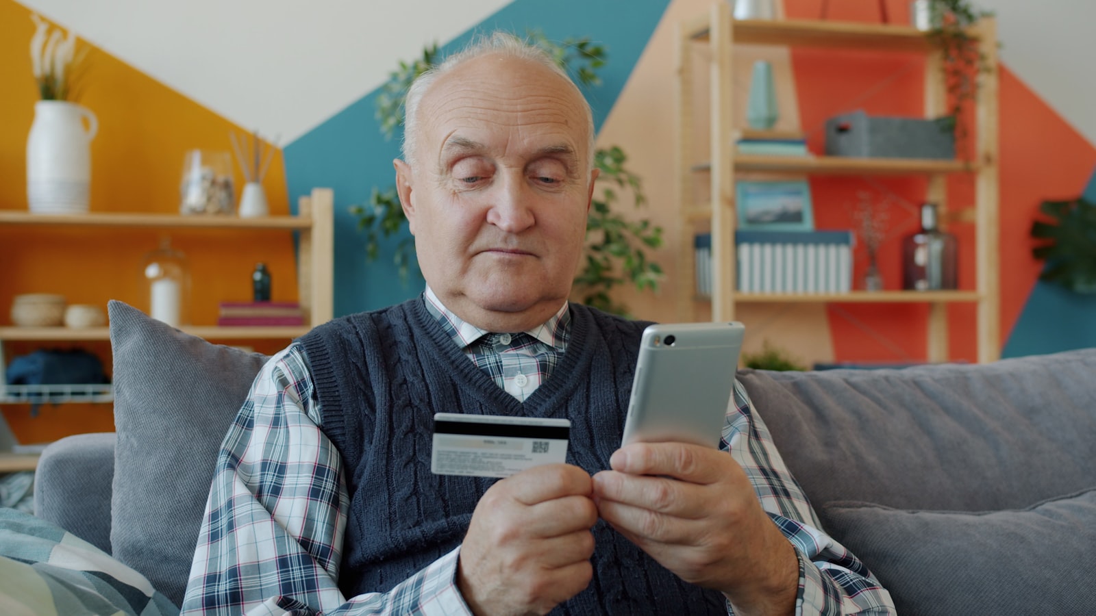 Barrierefreie Website: Was das BFSG für dein Unternehmen bedeutet 1 Älterer Mann hält eine Kreditkarte und ein Smartphone beim Online-Einkauf